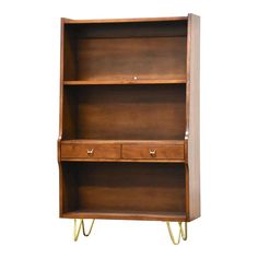 a wooden bookcase with two drawers on one side and three brass legs, against a white background