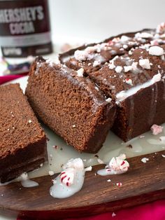 chocolate cake with white frosting and peppermints on a wooden platter next to a bottle of hershey's cocoa