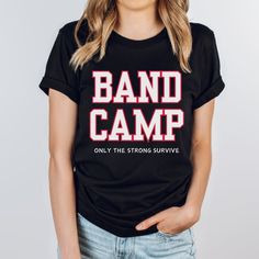 Survived band camp? Show off your battle scars (and your sense of humor) with our hilarious "Band Camp, Only the Strong Survive" t-shirt! Perfect for band geeks who know that surviving band camp takes more than just musical talent--it takes sheer willpower! Marching in the sun, carrying heavy instruments, and perfecting that choreography? Yep, you've earned this shirt. Wear it with pride and a knowing smile--because only the strong survive band camp! WHAT IS IT MADE OF? -100% Airlume combed and ring-spun cotton (heather colors vary) -Lightweight fabric (4.2 oz/yd² (142 g/m²) -Classic fit -Tear-away label -Runs true to size HOW DO I ORDER?  -Look over the size chart -Select your desired size as well as color -Click the Add to cart button and continue to checkout -Add Your Shipping and Payme Band Merch T-shirt With Slogan For Music Festivals, College Band Merch T-shirt With Letter Print, Band Merch T-shirt For Music Festival With Text Print, Hip Hop T-shirt With Band Logo For Concerts, Hip Hop Band Logo T-shirt For Concert, Band Shirt Ideas, Marching Band Shirts, Band Camp, Band Mom