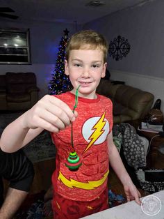 a young boy wearing a red shirt holding a green string