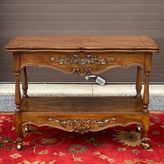 an old wooden table with a remote control on it's shelf and red carpet