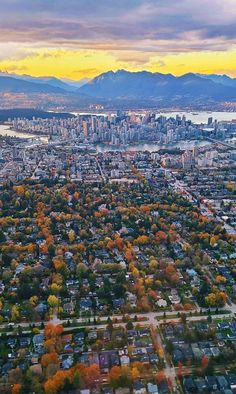 an aerial view of a city with mountains in the distance and trees on both sides