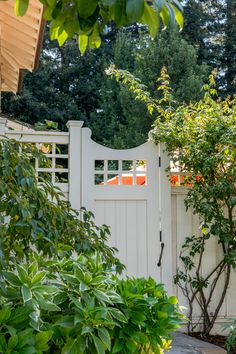 a white gate surrounded by trees and bushes