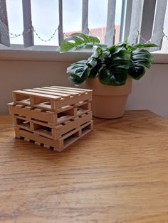 a wooden crate sitting on top of a wooden table next to a potted plant