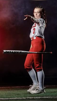 a girl in red and white uniform holding a baseball bat