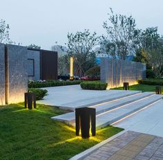 an outdoor area with steps, bushes and lights on the grass in front of it