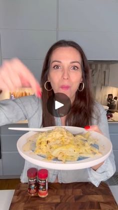 a woman holding a plate of food in front of her face and pointing to the camera