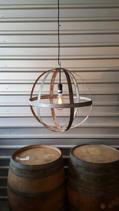 two wine barrels sitting next to each other in front of a wall with a light fixture hanging from it