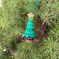 a green christmas tree ornament hanging from a pine tree