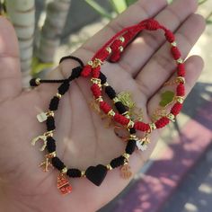 two red and black beaded bracelets are held in someone's hand