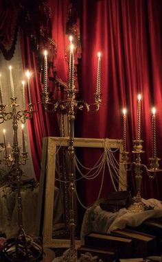 a room filled with lots of candles next to a red curtain