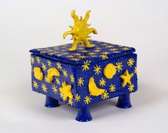 a blue box with yellow stars and moon decorations on it's lid, sitting in front of a white background