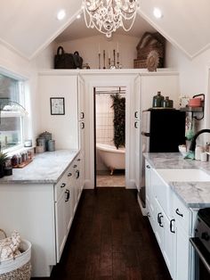 a kitchen with white cabinets and marble counter tops next to a bathtub in the corner