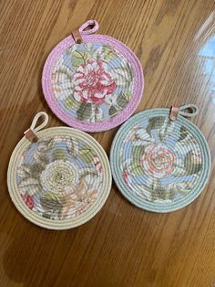 three woven coasters with flowers on them sitting on a wooden table next to each other