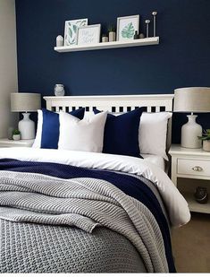 a bedroom with blue walls, white bedding and two lamps on the nightstands