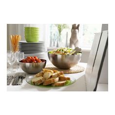 a table topped with plates and bowls filled with food next to silver utensils