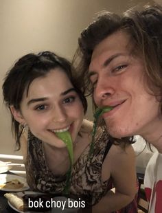 two people posing for a photo with food in front of their faces and one person holding something up to her mouth