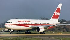 a large white and red jetliner sitting on top of an airport runway