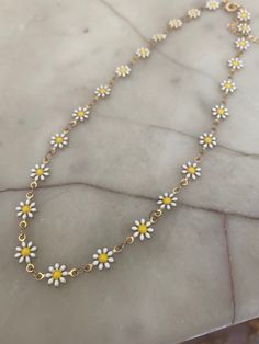 Raw brass daisy chain necklace with white and yellow enamel. The choker necklace measures 13 inches with a gold-plated lobster clasp and two inch extender. INTERNATIONAL BUYERS please choose the tracking option if you would like your order to be tracked. FREE tracking upgrade with 3 items or more purchased. JEWELLERY CARE please don't wear plated jewellery in the shower, bath or swimming for the plating to last longer. Trendy White Flower Necklace For Summer, Gold Flower Necklace For Summer Gifts, Trendy Yellow Flower Shaped Jewelry, Trendy Yellow Flower-shaped Jewelry, Gold Daisy Jewelry For Summer, Gold Daisy-shaped Jewelry For Summer, Gold Flower Necklace For Summer, Adjustable Yellow Daisy Jewelry, Adjustable Gold Flower Necklace For Spring