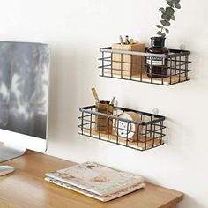 two metal baskets are hanging on the wall next to a computer monitor and mouse pad