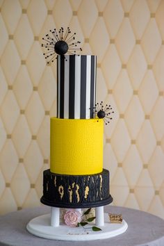 a three tiered cake with black, white and yellow stripes on it's side