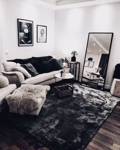 a black and white photo of a living room with couches, rugs and pictures on the wall