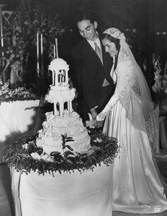 an old black and white photo of a bride and groom cutting their wedding cake