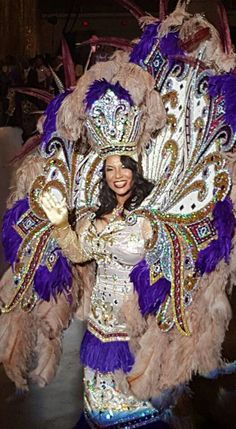 a woman in a purple and white costume with feathers on her head, posing for the camera