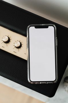 a cell phone sitting on top of a black case next to a white button and two knobs