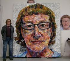 a woman standing next to a large portrait made out of bottle caps