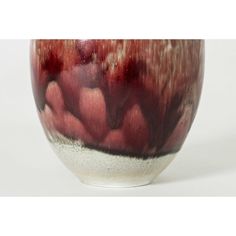 a red and white vase sitting on top of a table