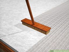 a broom sitting on top of a white floor next to a wooden pole with a long handle