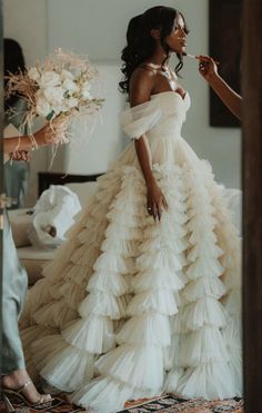 a woman in a wedding dress is brushing her teeth while another woman stands near her