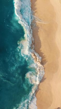 an aerial view of the ocean and beach with waves coming in from the sand,