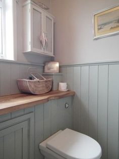 a white toilet sitting in a bathroom next to a sink under a window on top of a wooden counter