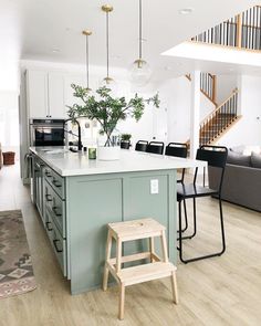 a kitchen island with stools in front of it and stairs to the second floor