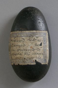 an old egg with writing on it sitting next to a white wall and gray background