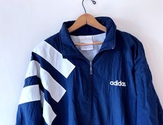 90’s ADIDAS streetwear sportswear windbreaker jacket size XLDESCRIPTION:Color: Navy Blue/WhiteStyle: Long Sleeve, Zip Front, Elastic Ribbed Cuffs & Bottom, Lined, 2 Slip Pockets, Rollaway HoodMeasurements:Entire Garment Length: 30 inchesPit to Pit: 25 inchesSleeve: 24 inchesFabric: 100% NylonSize: LargeCONDITION:Good condition, some wearMinor markings & discoloring on sleeve, see photosTAG DETAILS:Made by AdidasMade in Taiwan Sporty Adidas Windbreaker For Winter, Hooded Three-stripes Windbreaker For Streetwear, 90s Style Streetwear Track Jacket For Spring, Casual Adidas Windbreaker With Long Sleeves, Vintage Spring Sports Windbreaker, Adidas Logo Outdoor Windbreaker With Long Sleeves, Hooded Streetwear Windbreaker With Three Stripes, Hooded Windbreaker With Three Stripes For Streetwear, Streetwear Long Sleeve Windbreaker With Three Stripes