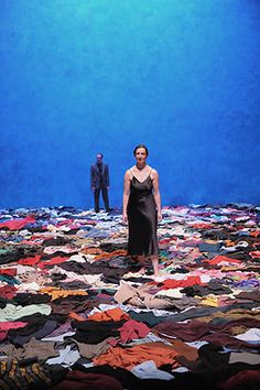 a woman standing on top of a pile of clothes in front of a blue background