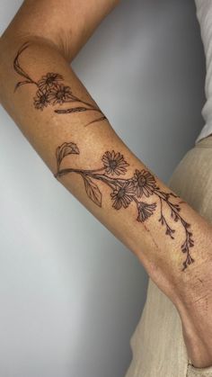 a woman's arm with flowers and leaves tattooed on the side of her arm