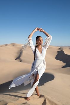 a woman is dancing in the sand dunes