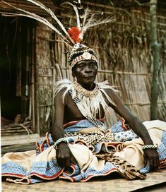 an african man sitting on the ground wearing a headdress