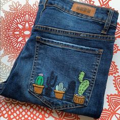 a pair of jeans with cactus embroidered on them