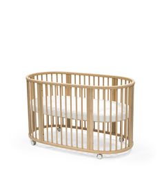 a wooden baby crib with white sheets on the sides and wheels, against a white background