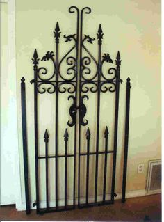 an iron gate is shown in the corner of a room with white walls and wood floors