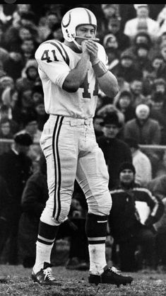 an old black and white photo of a football player holding a ball in his hands