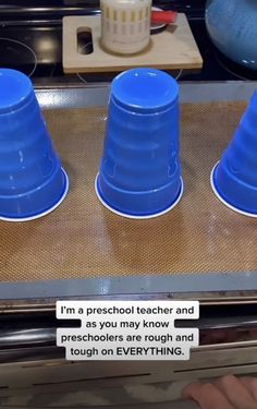 three blue cups sitting on top of a stove next to a sign that says i'm a preschool teacher and so you may know