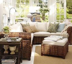 a living room with wicker furniture and large windows in the background, along with white walls