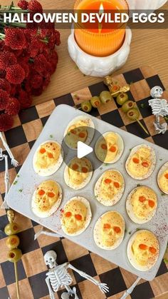 halloween deviled eggs on a baking tray with skeletons and strawberries in the background