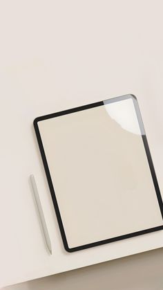 a white desk with a black frame and pen next to it, on top of a white surface